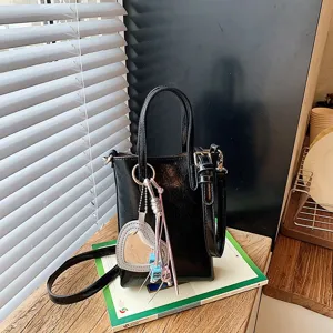 Black patent leather shoulder crossbody phone bag for women, chic mini tote purse with charm.