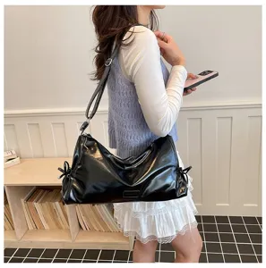 Vue détaillée d'un sac porté épaule noir brillant élégant avec bandoulière réglable.