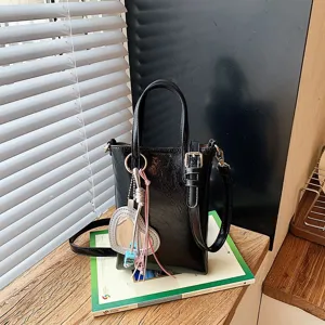 Chic black glossy phone crossbody bag with cute heart pendant, versatile niche design for women.