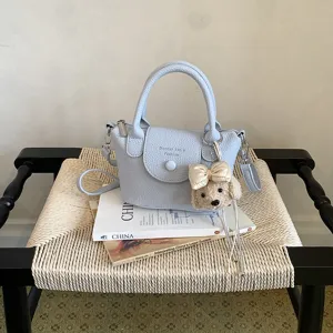 Chic borsa a secchiello a tracolla in pelle azzurra con ciondolo cucciolo per donna.