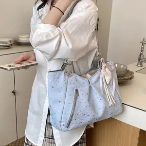 Light blue tote bag detail, featuring star print, front zipper pocket and cute ribbon pendant.
