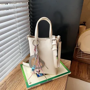 Detail view of stylish minimalist white mini shoulder crossbody phone bag with cute charm.