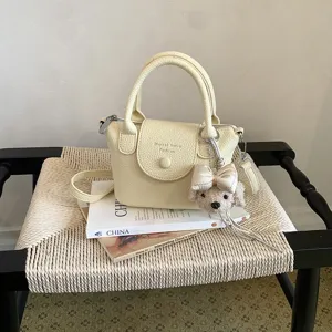 Vista dettagliata di una borsa a secchiello in pelle gialla chiara con ciondolo a cucciolo.