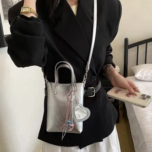 Silver metallic crossbody phone bag with heart mirror pendant, chic niche design fashion accessory.