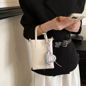 Detailed view of white mini phone bag with heart charm, stylish crossbody accessory.