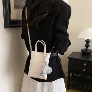 Chic small white crossbody phone bag with top handle, heart charm and bead details.