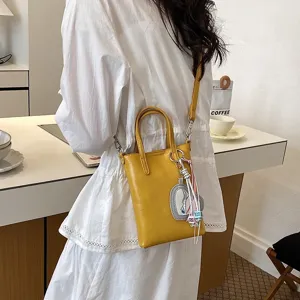 Chic yellow crossbody phone bag with charm detail, perfect for daily commute and style.