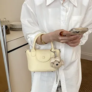 Vista dettagliata della mini borsa secchiello trendy in pelle gialla con simpatico ciondolo cane.