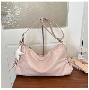 Vue détaillée du sac à épaule rose stylé avec breloque étoile sur une belle table en bois.