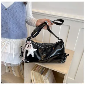 Détail du sac fourre-tout noir brillant avec fermetures à glissière et pendentif étoile.