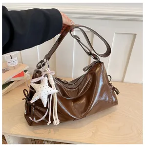 Détail de sac bandoulière coussin marron brillant rétro, sac élégant avec pendentif étoile.