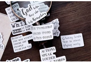 Detailed shot of decorative black and white English quote stickers spread on a wooden table.