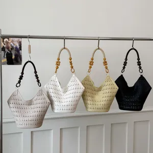 Detaillierte Ansicht stilvoller, gelochter Schultertaschen mit Perlenhandgriffen in Farben.