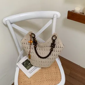 Beige Schultertasche mit Lochmuster, Holzperlen-Griff und elegantem Anhänger für Alltag.