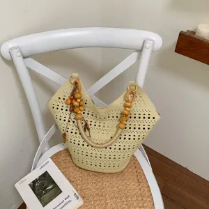 Detailaufnahme einer stilvollen gelben Schultertasche mit Holzperlen und Lochmuster.
