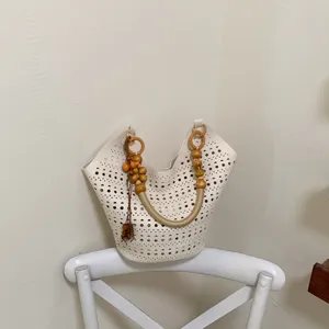 Weisse hohle Ledertasche mit Holzperlen Griff und Quasten Detail für Damen Sommer.