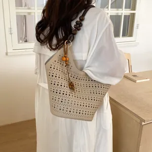 Beige perforierte Schulter-Eimer-Tasche mit Holzperlenriemen und Quasten-Detail.