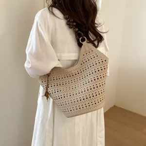 Detailansicht der beigen Schultertasche mit Lochmuster und dekorativem Perlenriemen.