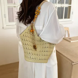 Nahaufnahme einer geflochtenen Eimer Tasche mit Holzperlenriemen in Alltagsszene.
