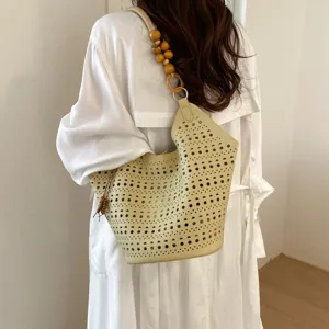 Beige Schultertasche Detail mit Lochmuster und elegantem Holzperlen-Riemen fuer den Alltag.