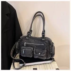 Detailansicht der Jeans-Schultertasche mit mehreren Taschen, Reißverschlüssen und Nieten.