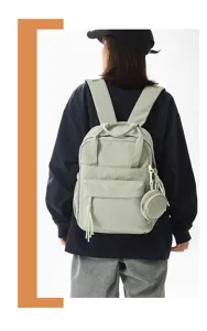 Vue détaillée du sac à dos décontracté vert sauge avec poche avant et mini porte-monnaie.