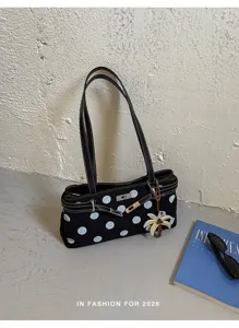 Vue détaillée du sac à épaule noir à pois avec serrure métallique et charmant pendentif.