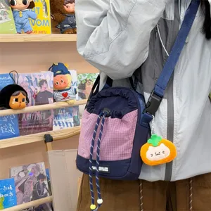 Casual crossbody bag detail showing the durable strap, plaid pattern, and cute plush cat pendant.