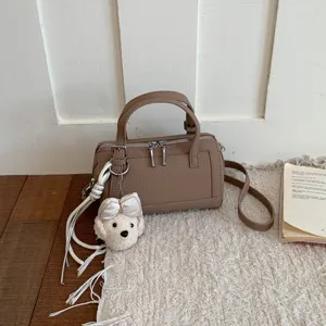 Chic brown leather pillow shoulder bag with cute plush puppy charm, versatile commuter handbag.