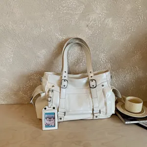 Vista dettagliata della grande borsa a spalla in pelle verniciata bianca con fibbie chic.