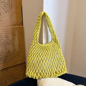 Detailed view of yellow woven macrame shoulder bag showcasing intricate hollow mesh texture.