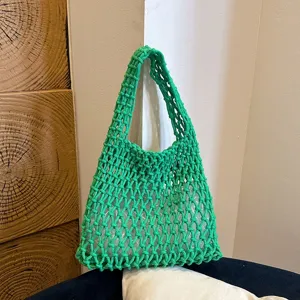 Green woven handbag detail view, showcasing intricate macrame mesh design and stylish underarm strap.