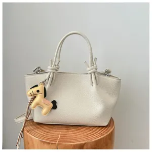 Gros plan détaillé du sac seau en cuir texturé de qualité avec charm cheval et poignée.