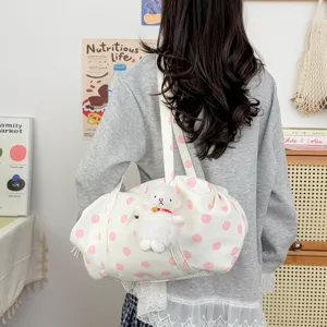 Dettaglio borsa a tracolla casual tessuto bianco con pois rosa e ciondolo di peluche.
