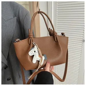 Vue détaillée d'un sac seau en cuir marron avec poignées nouées et charm cheval.