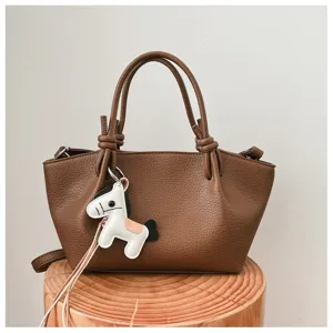Vue détaillée du sac à main marron en cuir avec charmant pendentif cheval pour un style chic.