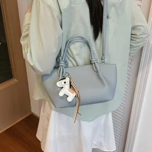 Vue détaillée du sac à bandoulière bleu clair élégant avec pendentif cheval et poignées.