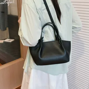 Vue de détail élégante du sac à épaule en cuir noir avec poignée nouée tendance.