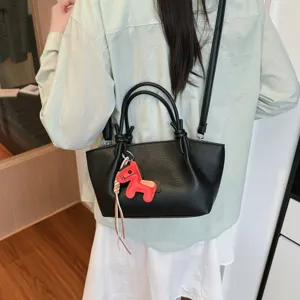 Élégant sac seau en cuir noir avec charm cheval rouge pour femmes chic et tendance.