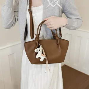Vue détaillée du sac seau bandoulière minimaliste en cuir marron avec charm cheval.