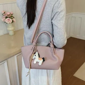 Vue détaillée d'un sac à bandoulière en cuir rose élégant avec joli charm cheval au quotidien.
