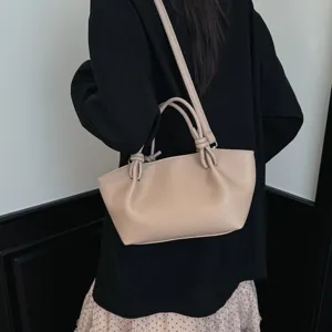 Gros plan détaillé du sac à main d'épaule en cuir minimaliste avec des poignées nouées.