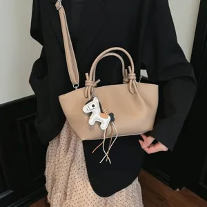 Sac à bandoulière minimaliste en cuir beige avec poignées nouées chics et pendentif cheval.