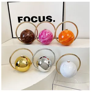 Detailed view of spherical evening bags with metal ring handles, available in marble and mirror finishes.