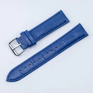 Gros plan détaillé du bracelet de montre en cuir bleu avec texture et boucle argentée.
