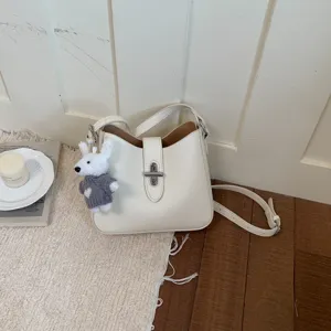 Detailansicht der minimalistischen weißen Leder-Eimer-Tasche mit süßem Hasenanhänger und Schloss.