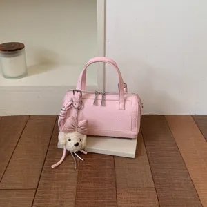 Close-up of a stylish pink leather pillow bag featuring a cute plush puppy keychain.