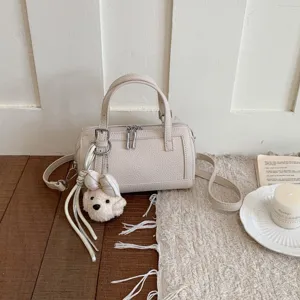 Detailed shot of chic beige pillow handbag with cute puppy charm and stylish pebbled texture.