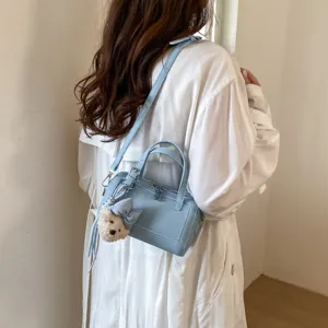 Light blue shoulder pillow bag detail showing premium PU leather texture and cute bear pendant.