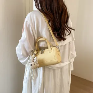 Chic yellow cylindrical shoulder bag, premium crossbody pillow bag with cute plush bear charm.